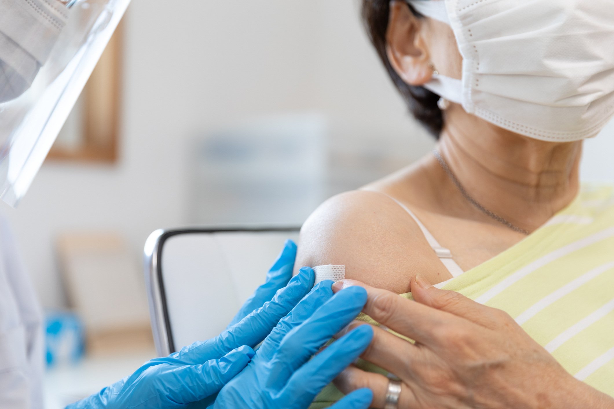 Healthcare worker places bandage on woman's arm after giving a vaccine