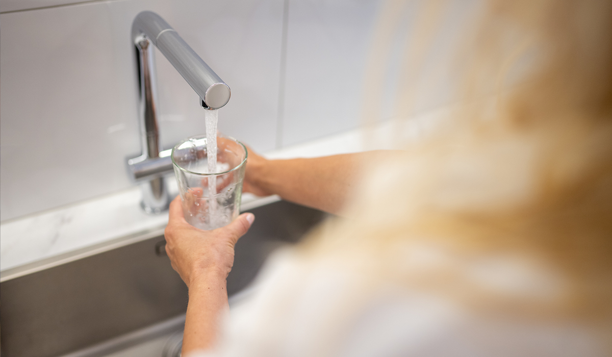 A woman fills a glass at a sink