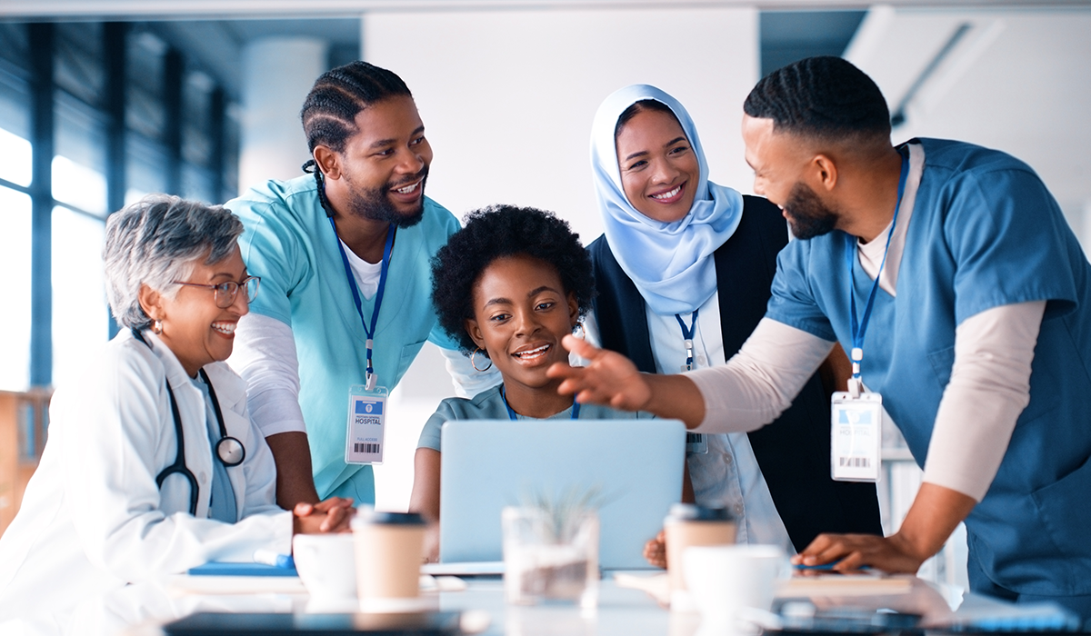 Healthcare workers gather around a computer and talk